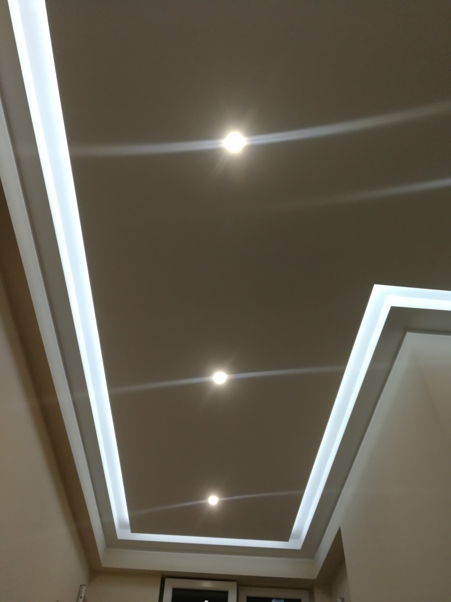 Nowoczesny sufit podwieszany z oświetleniem LED punktowym i obwodowym, widok z dołu.