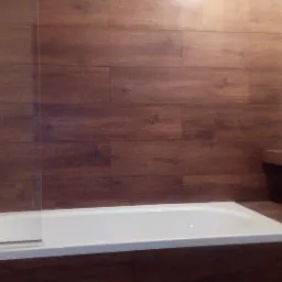 Nowoczesna łazienka z drewnopodobnymi płytkami na ścianie, białą wanną i grzejnikiem drabinkowym.