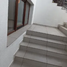 Wykończone kafelkami schody wewnętrzne z brązowymi oknami i metalową balustradą na górze.