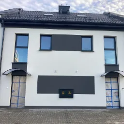 Fasada szeregowca z dwoma wejściami, drzwi zabezpieczone folią malarską, nowoczesna architektura z elementami w kolorze grafitowym.