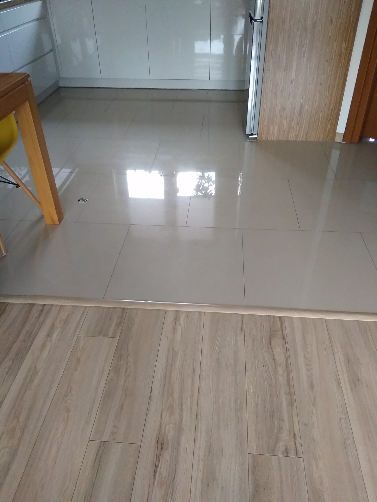 Połączenie płytek podłogowych w kuchni z panelami podłogowymi w Biłgoraju, widoczna listwa przypodłogowa oddzielająca oba typy podłóg.