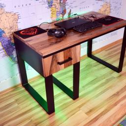 Montex - Drewniane biurko gamingowe z czarną metalową ramą, na blacie laptop, klawiatura, słuchawki i dwie podkładki pod mysz, oświetlenie LED w kolorze zielonym, na ścianie mapa świata.