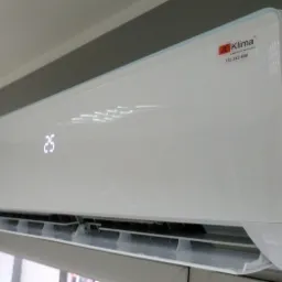 Biała jednostka klimatyzacyjna z wyświetlaną temperaturą 25 stopni, zamontowana na ścianie w pomieszczeniu.