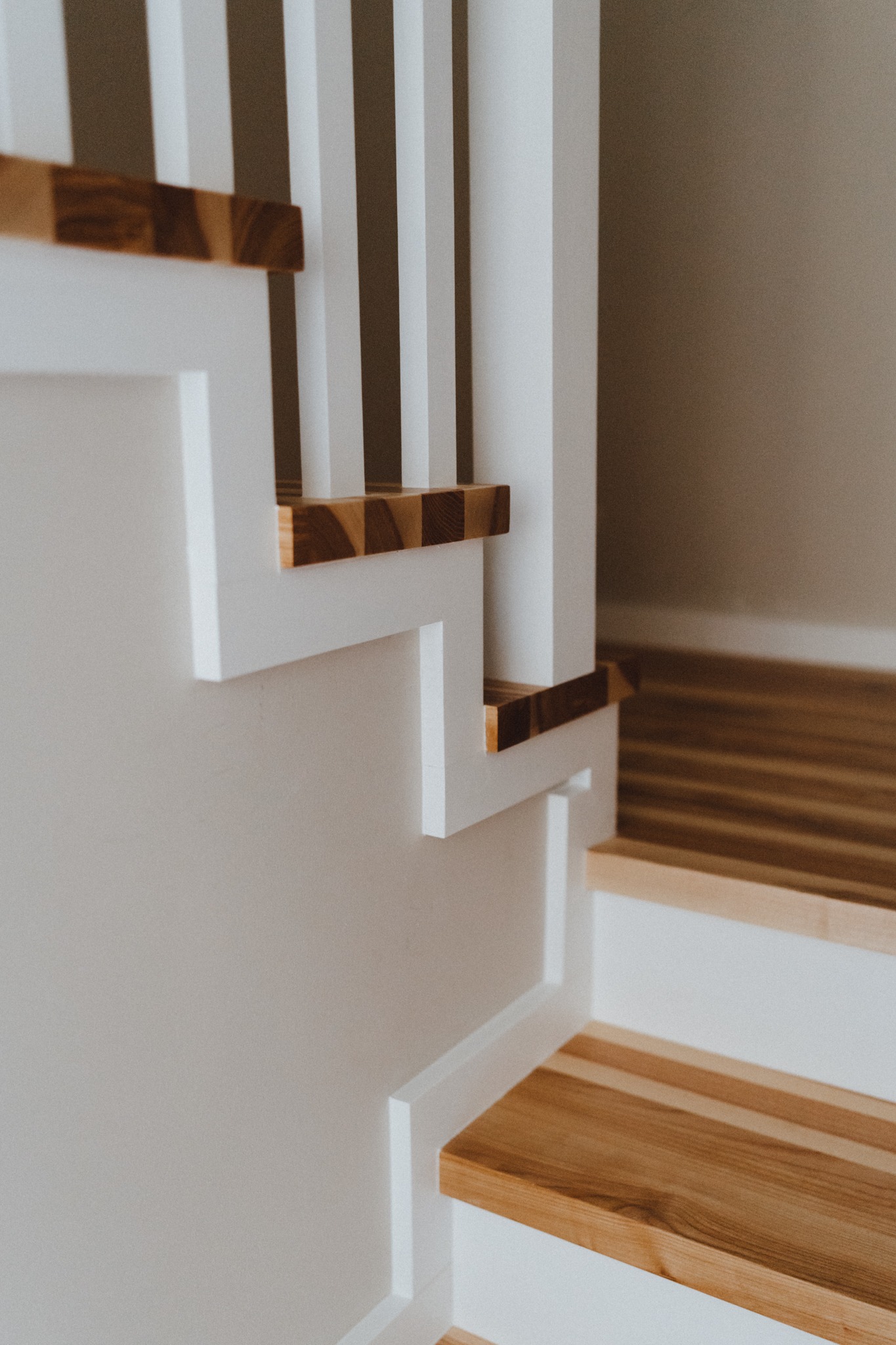 Białe schody z drewnianymi stopniami i balustradą, minimalistyczny design, jasne wnętrze.