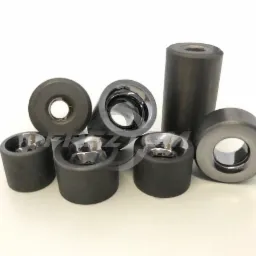 Zestaw precyzyjnych, szarych, metalowych tulei i pierścieni z polerowanymi wnętrzami na białym tle, widoczne odbicia światła.