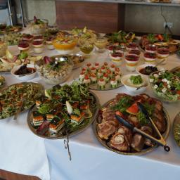 Jadłodajnie Polskie Sp. z o.o. - Bogato zastawiony stół cateringowy z różnorodnymi przystawkami: sałatki, roladki mięsne z szczypcami, mini kanapeczki, desery w szklankach i inne przekąski na srebrnych paterach.