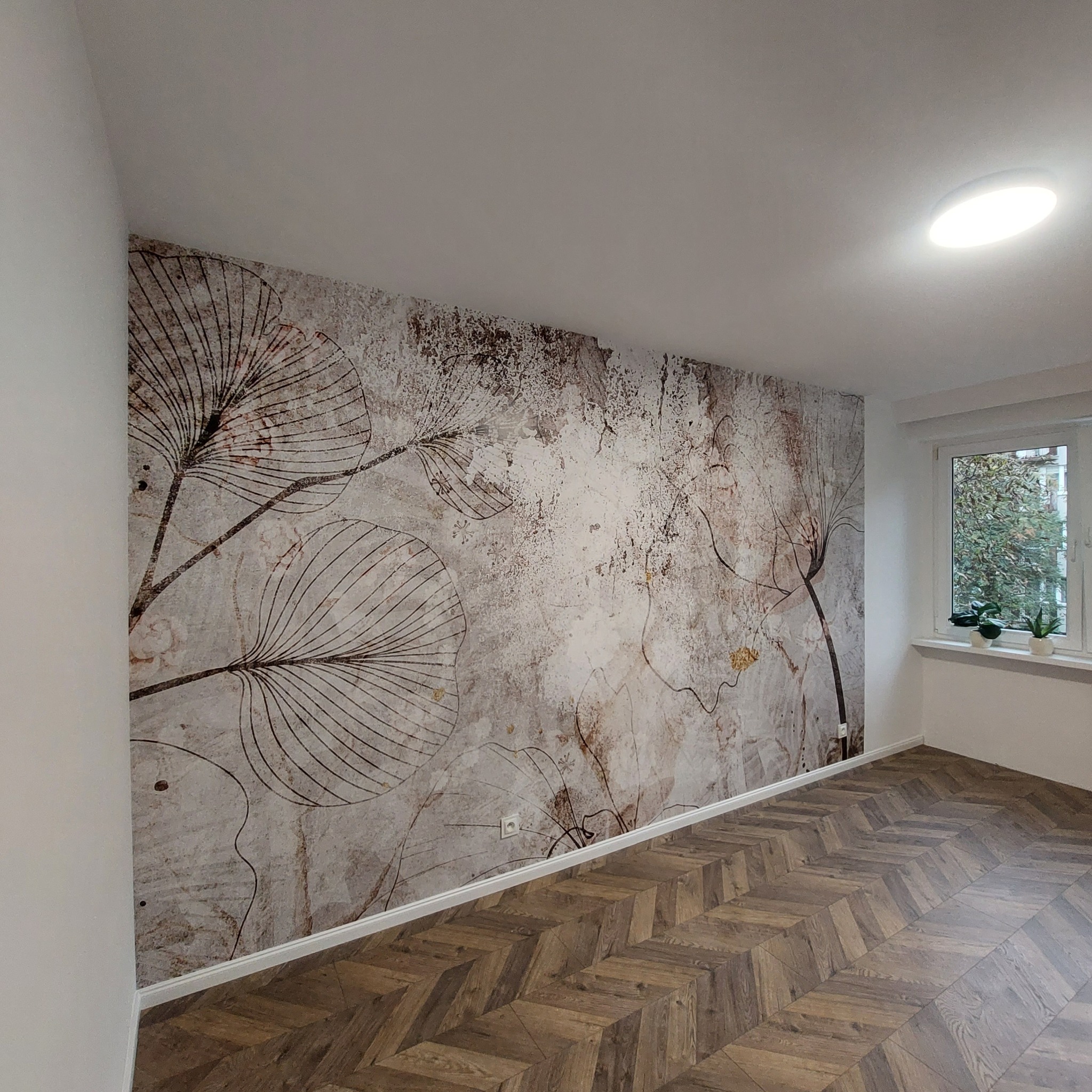 Pokój z wzorzystą tapetą w stylu vintage z motywem roślinnym i parkietem ułożonym w jodełkę.