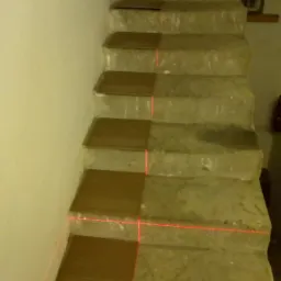 Renowacja schod&oacute;w betonowych z częściowo położonymi brązowymi płytkami, wyznaczona laserem linia pozioma i pionowa, widok z g&oacute;ry w trakcie remontu.