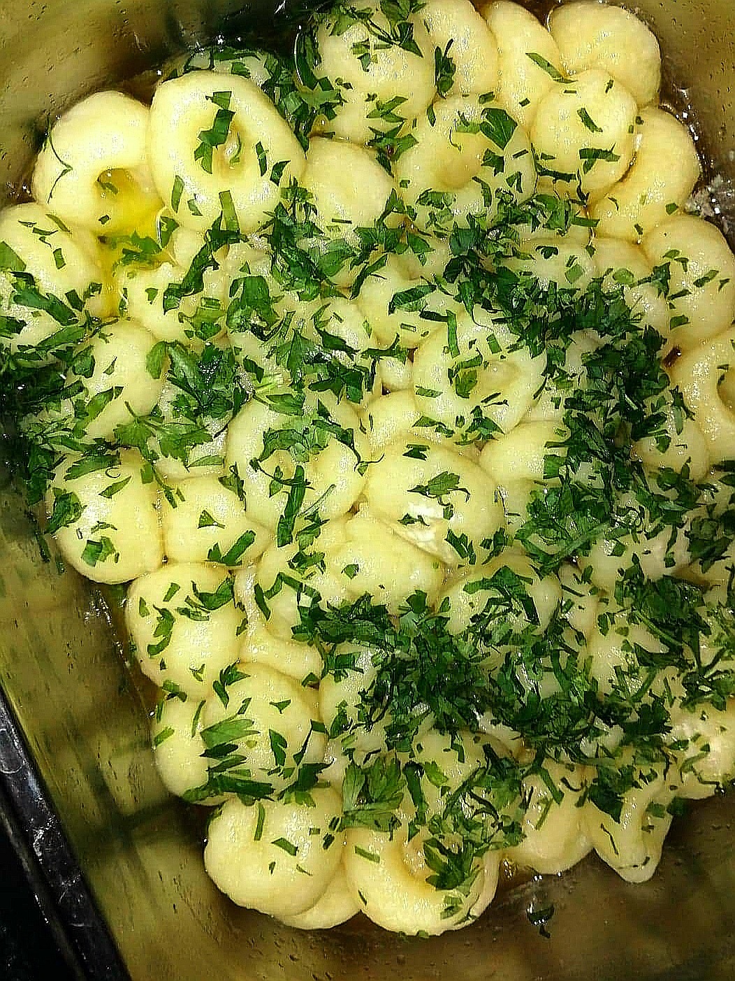 Kopytka z masłem i posiekaną zieloną pietruszką, przygotowane w Mścicach.