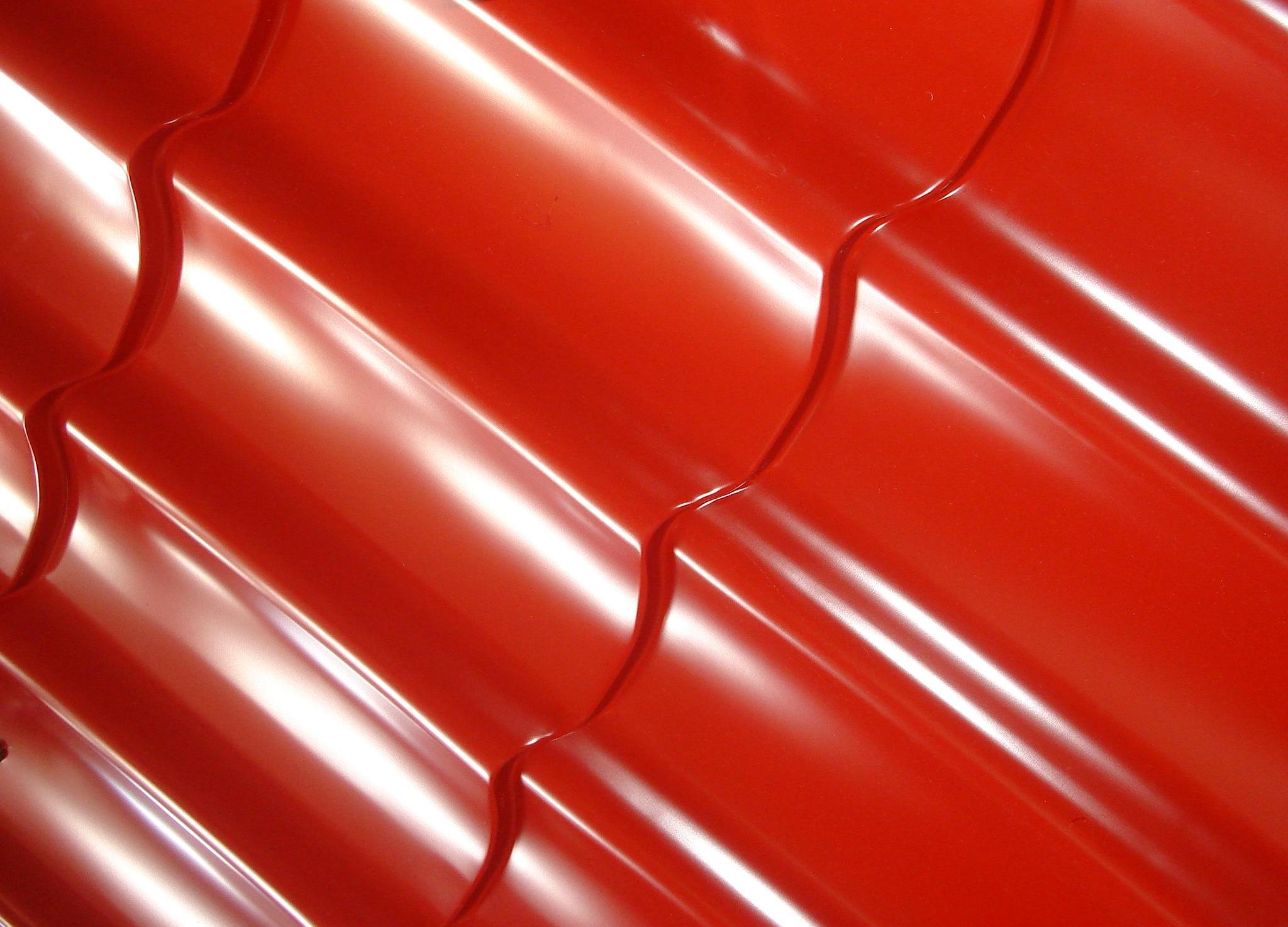 Czerwona blachodachówka modułowa z widocznymi przetłoczeniami i połyskiem, ułożona pod kątem, oświetlona z góry.