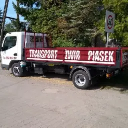 Ciężarówka z napisem 'Transport Żwir Piasek' zaparkowana w Poznaniu, widoczny znak ograniczenia prędkości do 30 km/h.