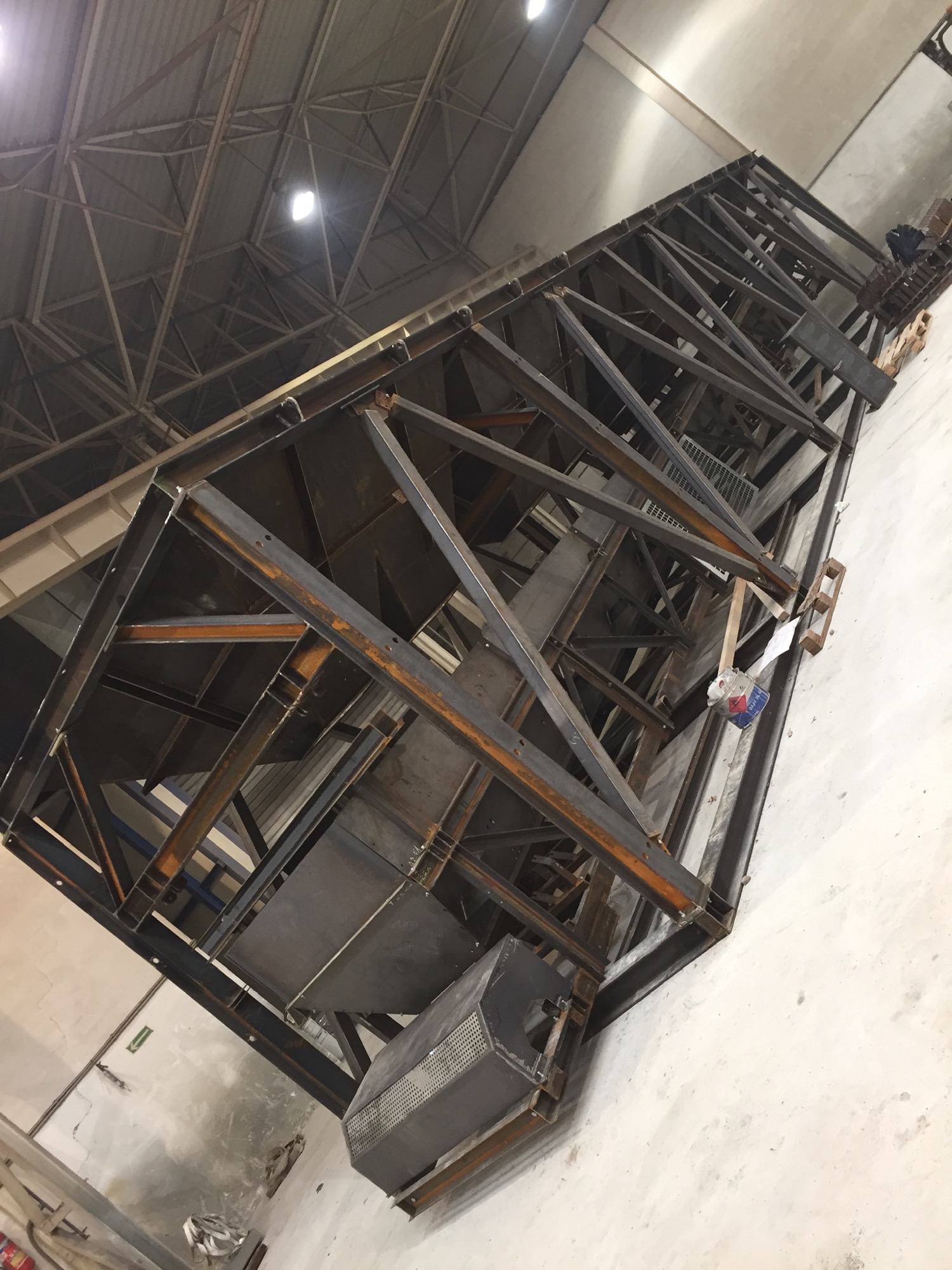 Konstrukcja metalowa z profili stalowych w hali produkcyjnej, widoczne spawy i elementy montażowe.