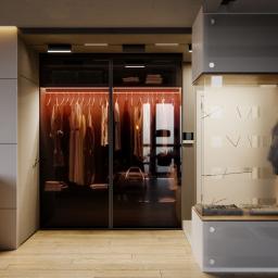 KGM Design Group - Nowoczesna garderoba z przesuwnymi, przyciemnianymi drzwiami, podświetleniem LED wewnątrz i minimalistycznym siedziskiem z wieszakiem na ubrania przy wejściu, na drewnianej podłodze.