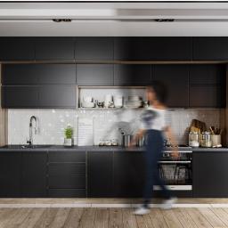 KGM Design Group - Nowoczesna kuchnia z czarnymi matowymi frontami szafek, drewnianym akcentem, białymi płytkami na ścianie, drewnianą podłogą, oświetleniem punktowym i rozmytą sylwetką osoby w ruchu.