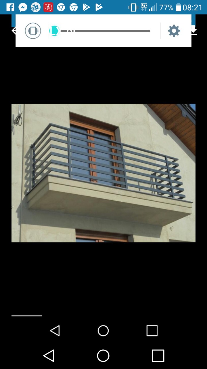 Balkon z szarą balustradą nierdzewną o poziomym układzie prętów, zamontowaną na betonowej płycie balkonu, z oknem w tle, widok z dołu.