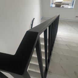 Jakub Semba - Nowoczesna, czarna balustrada schodowa z metalu, widok z góry na marmurowe schody. Minimalistyczny design, jasne wnętrze z oknem dachowym.