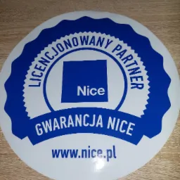 Okrągła naklejka z logo Nice, informująca o licencji partnerskiej i gwarancji, umieszczona na drewnianej powierzchni.