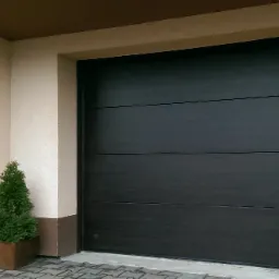 Nowoczesna, segmentowa brama garażowa w kolorze antracytu, z delikatnym wzorem drewna, umieszczona w elewacji budynku z jasnym tynkiem i małym, dekoracyjnym drzewkiem iglastym w donicy po lewej...