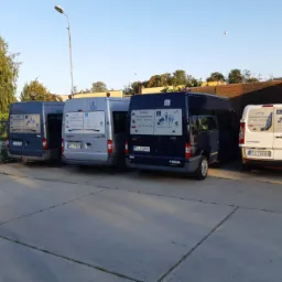 Cztery busy różnych marek i kolorów zaparkowane obok siebie, z widocznymi oznaczeniami o przystosowaniu do przewozu osób niepełnosprawnych, w tym osób na wózkach inwalidzkich. Na każdym busie...