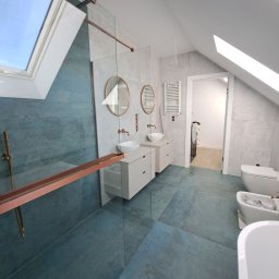 G&G sp.z o.o. - Nowoczesna łazienka na poddaszu z kabiną prysznicową, umywalkami na szafkach i oknami dachowymi. Dominuje niebiesko-szara kolorystyka z akcentami miedzianymi.