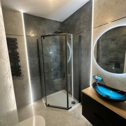 Fach-Bud - Nowoczesna łazienka z kabiną prysznicową w czarnej ramie, umywalką w odcieniach niebieskiego i okrągłym lustrem z podświetleniem LED.