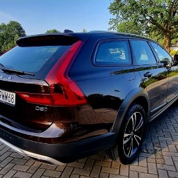 2KB AUTO DETAILING - Ciemnobrązowe Volvo V60 Cross Country zaparkowane na brukowanej nawierzchni, widok z tyłu, z widocznymi elementami karoserii i oponami terenowymi.