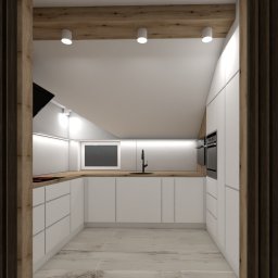 Venosfera Anna Dąbrowska - Nowoczesna kuchnia w bieli z drewnianym blatem i czarną armaturą, widoczna przez dekoracyjne drewniane panele w przejściu.