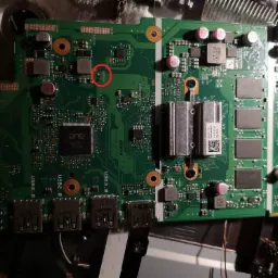 Widok z góry na płytę główną laptopa z widocznymi portami USB, elementami elektronicznymi i zaznaczonym czerwonym okręgiem potencjalnym uszkodzeniem lub obszarem wymagającym uwagi.