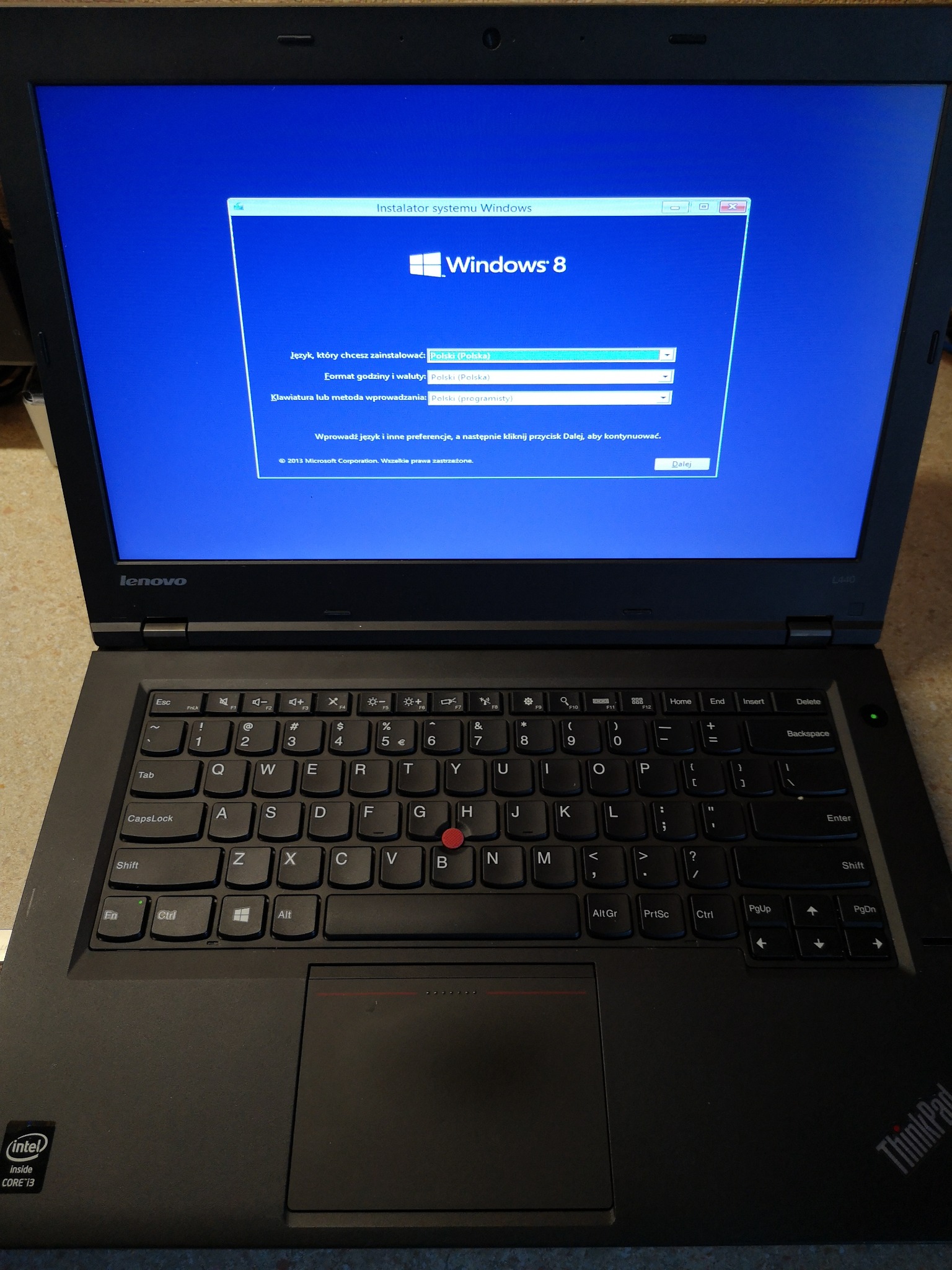 Laptop Lenovo ThinkPad z uruchomionym instalatorem systemu Windows 8, widoczny ekran wyboru języka, formatu czasu i waluty oraz metody wprowadzania, klawiatura z czerwonym trackpointem.
