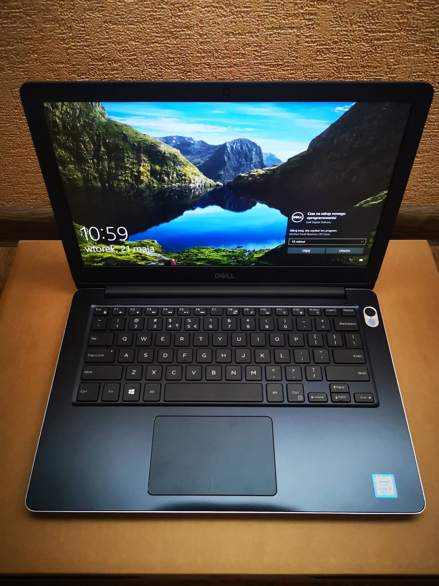 Otwarty laptop Dell z widocznym ekranem blokady z motywem górskiego jeziora, klawiaturą QWERTY i naklejką Intel Core i5 8th Gen w prawym dolnym rogu obudowy.