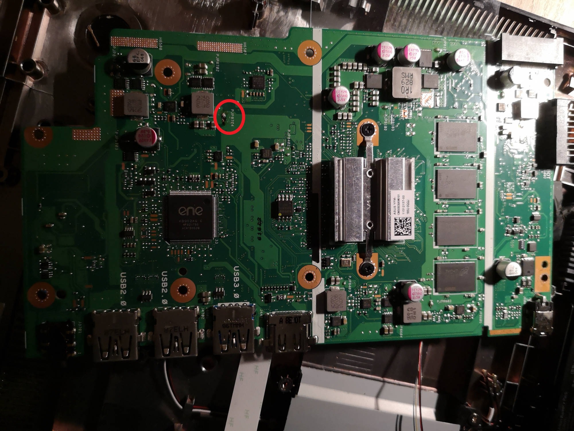 Widok z góry na płytę główną laptopa z widocznymi portami USB, elementami elektronicznymi i zaznaczonym czerwonym okręgiem potencjalnym uszkodzeniem lub obszarem wymagającym uwagi.