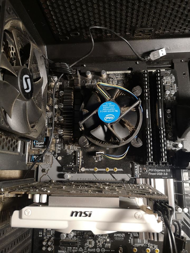 Wnętrze zakurzonego komputera stacjonarnego z widoczną płytą główną, kartą graficzną MSI, wentylatorem Intel i pamięcią RAM Corsair.