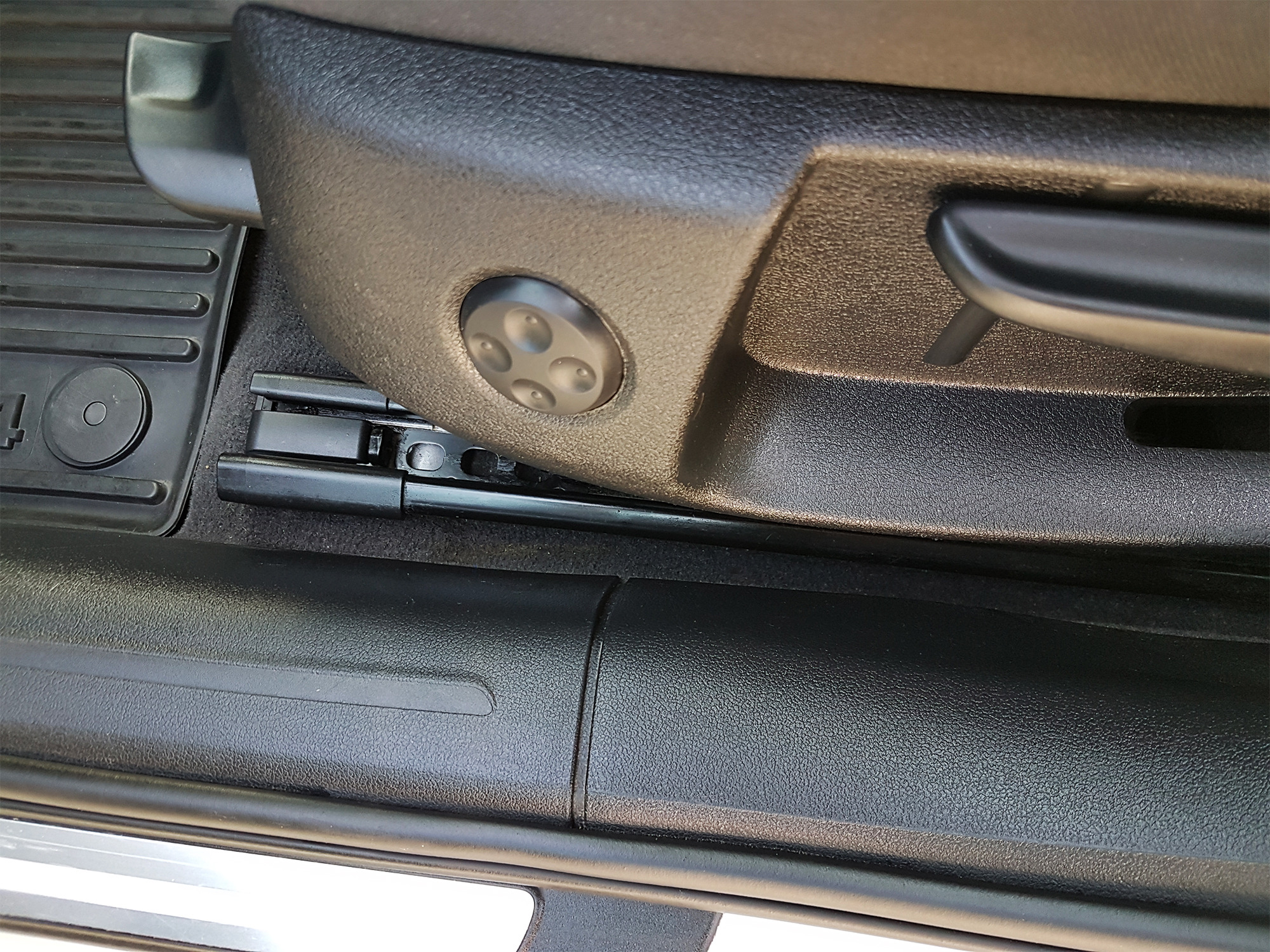 Regulacja fotela samochodowego w zbliżeniu, widoczny mechanizm przesuwania i panel sterowania ustawieniami.