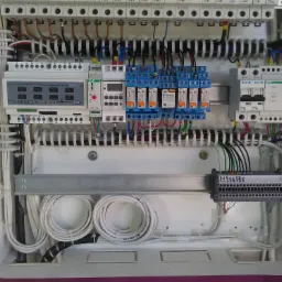 Rozdzielnica elektryczna z widocznymi elementami automatyki, zabezpieczeniami nadprądowymi, przekaźnikami i przewodami ułożonymi w sposób uporządkowany.