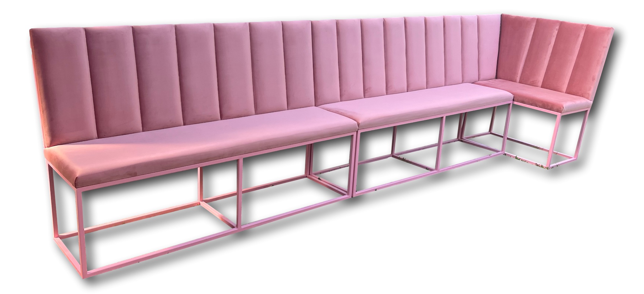Różowa, modułowa sofa tapicerowana z wysokim, pionowo dzielonym oparciem i metalową ramą, ustawiona pod kątem na białym tle.