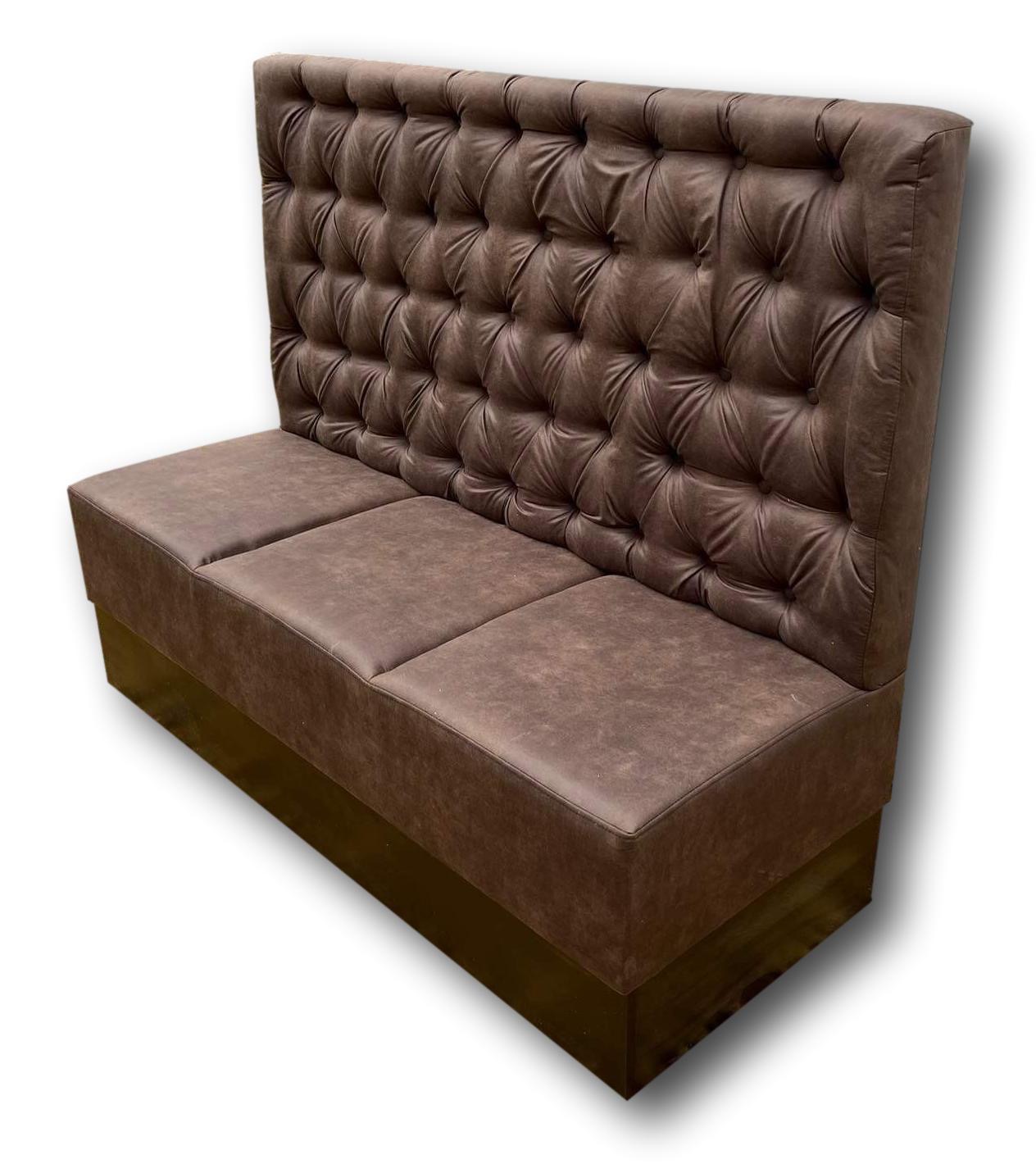 Brązowa, skórzana kanapa tapicerowana w stylu Chesterfield z wysokim oparciem, wykonana na wymiar w Kętach, z widoczną podstawą z ciemnego drewna.