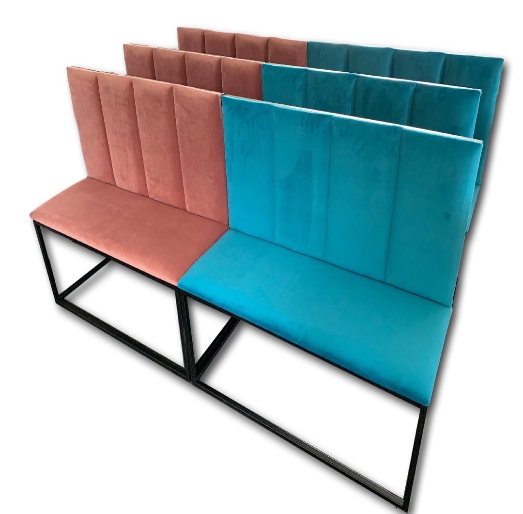 Rząd tapicerowanych ławek z weluru w kolorze koralowym i turkusowym, na czarnych metalowych nogach, ustawionych w rzędzie na białym tle.