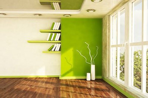 Nowoczesne wnętrze pokoju z zieloną ścianą i półkami na książki, drewniana podłoga, jasne okno z widokiem na zieleń.