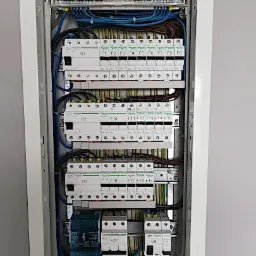 Otwarta skrzynka rozdzielcza z bezpiecznikami i okablowaniem, widok z przodu, schludne ułożenie przewodów.