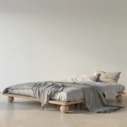 Minimalistyczna sypialnia z niskim łóżkiem na drewnianej ramie z okrągłymi nogami, przykrytym szarą pościelą i pledem w paski.