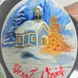 Ręcznie malowany talerz porcelanowy z zimowym pejzażem: ośnieżona kapliczka, choinka z brokatem i napis 'Wesołych Świąt'.