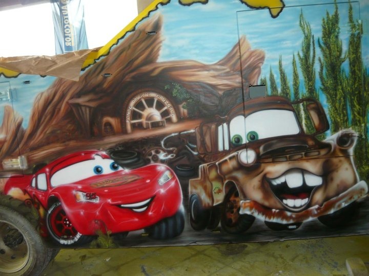 Airbrushing na holowniku Pomocy Drogowej: postacie Zygzaka McQueen i Złomka z filmu Auta na tle górskiego krajobrazu i warsztatu.