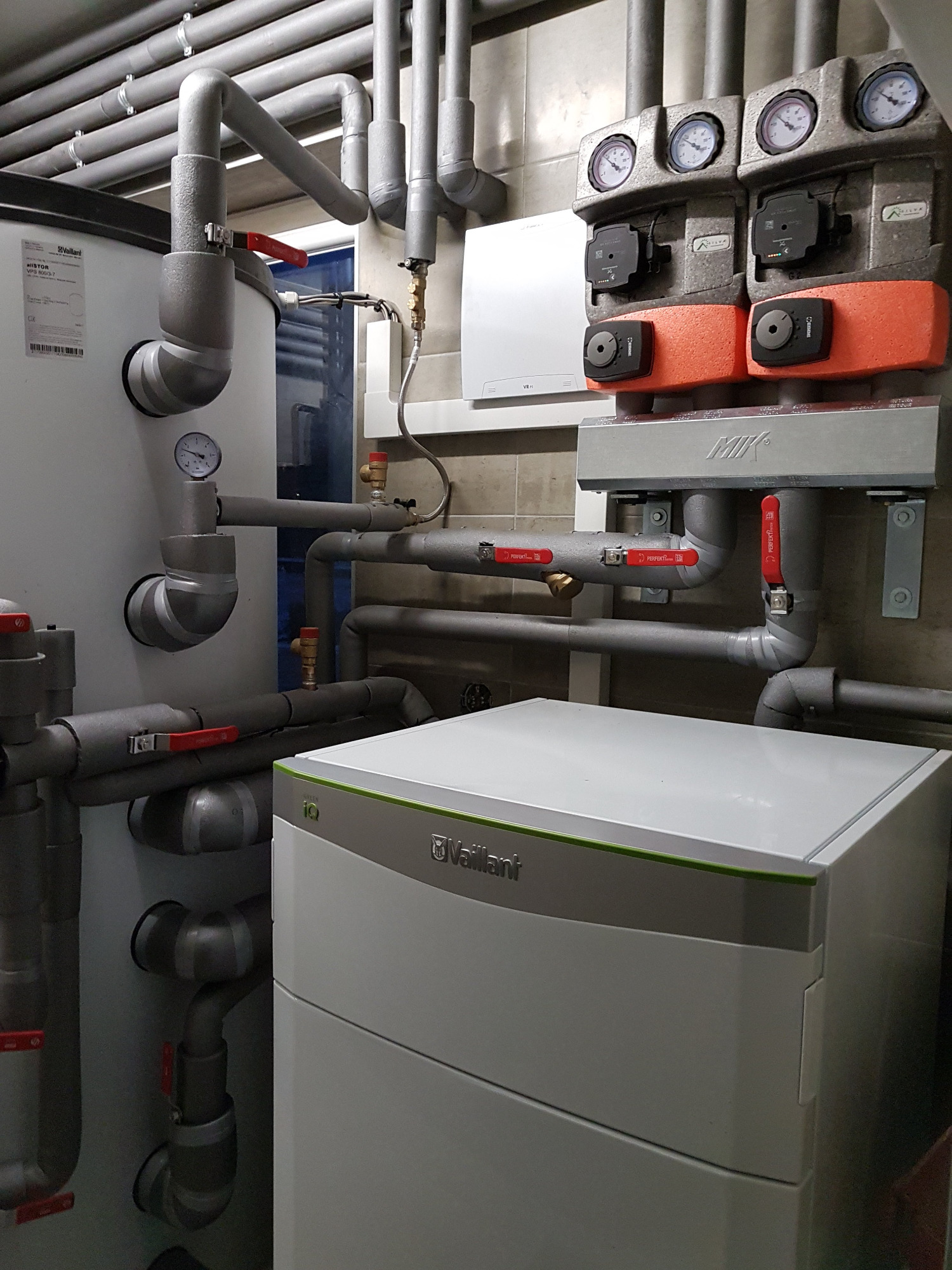 Węzeł cieplny z pompą obiegową, zaworami i manometrami, instalacja z rur izolowanych, zbiornik akumulacyjny Vaillant i piec gazowy Vaillant iQ Green.