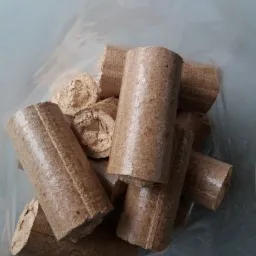 Cylindryczne brykiety drzewne w przezroczystym worku foliowym, widoczne charakterystyczne włókna drewna.