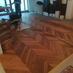 Avanti Design - Układanie parkietu w jodełkę z widocznymi narzędziami i materiałami budowlanymi w trakcie pracy.