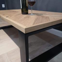 Avanti Design - Stolik kawowy z drewnianym blatem ułożonym we wzór jodełki, na metalowych, czarnych nogach, z butelką wina i kieliszkiem na blacie.