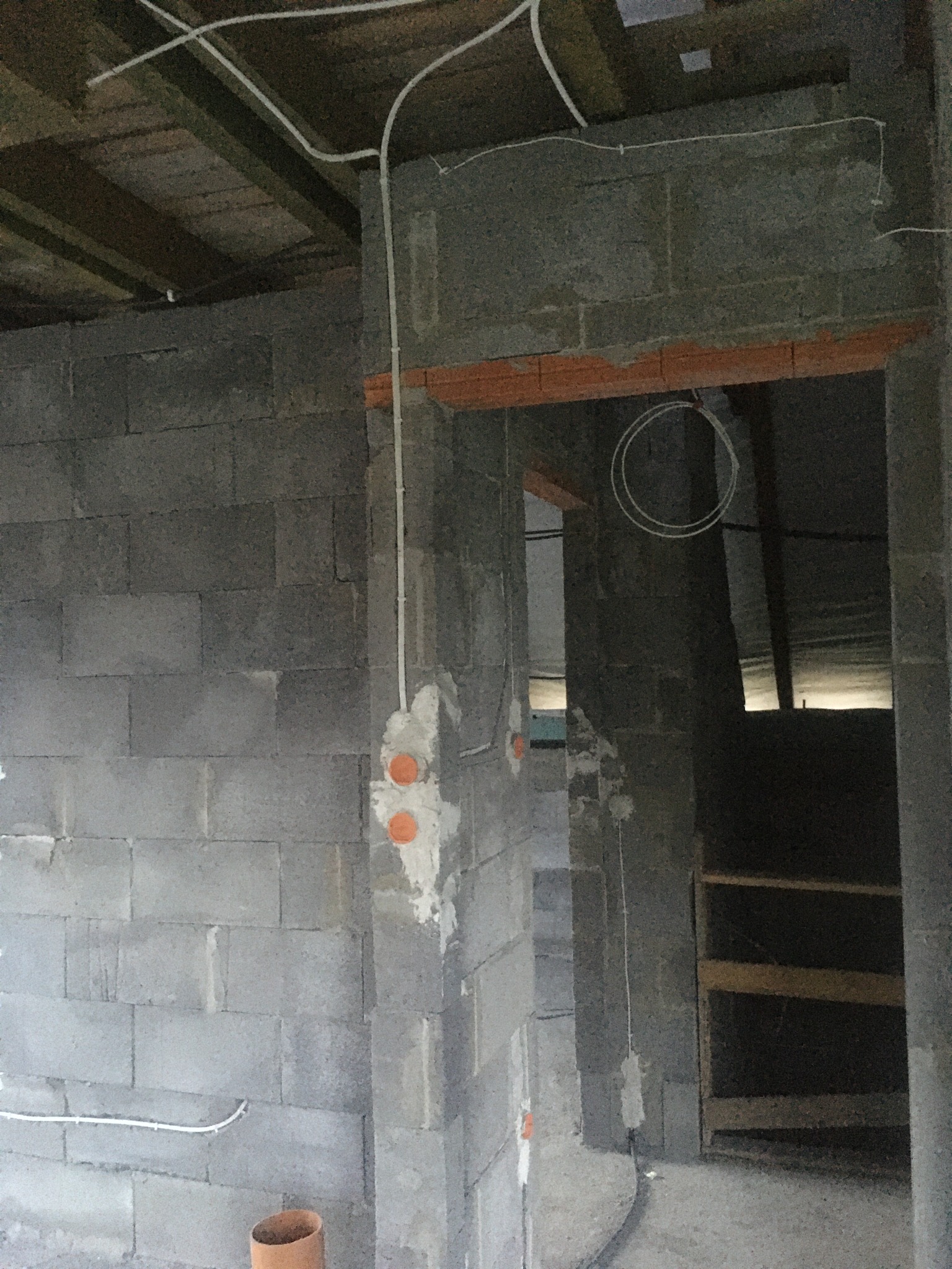 Surowy mur z widocznymi przewodami elektrycznymi i puszkami instalacyjnymi. Widoczne elementy instalacji podtynkowej w trakcie montażu.