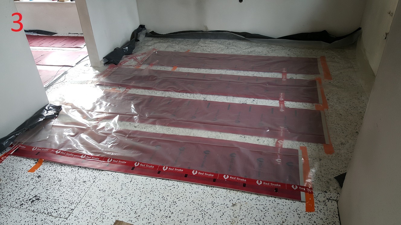 Przygotowanie do wylewki: folia budowlana zabezpiecza system ogrzewania podłogowego Red Snake, ułożony na posadzce z terazzo, widok z góry.