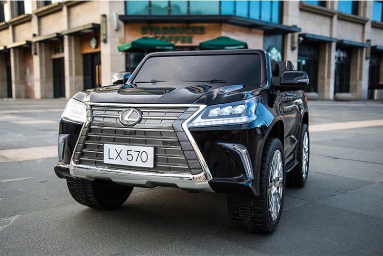 Czarny, elektryczny samochód dla dzieci Lexus LX 570 z chromowanym grillem i tablicą rejestracyjną LX 570, zaparkowany na zewnątrz budynku Starbucks.