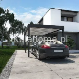 Nowoczesna wiata samochodowa z lamelami, chroniąca ciemny samochód Porsche Panamera, na tle minimalistycznego domu z szarą elewacją.